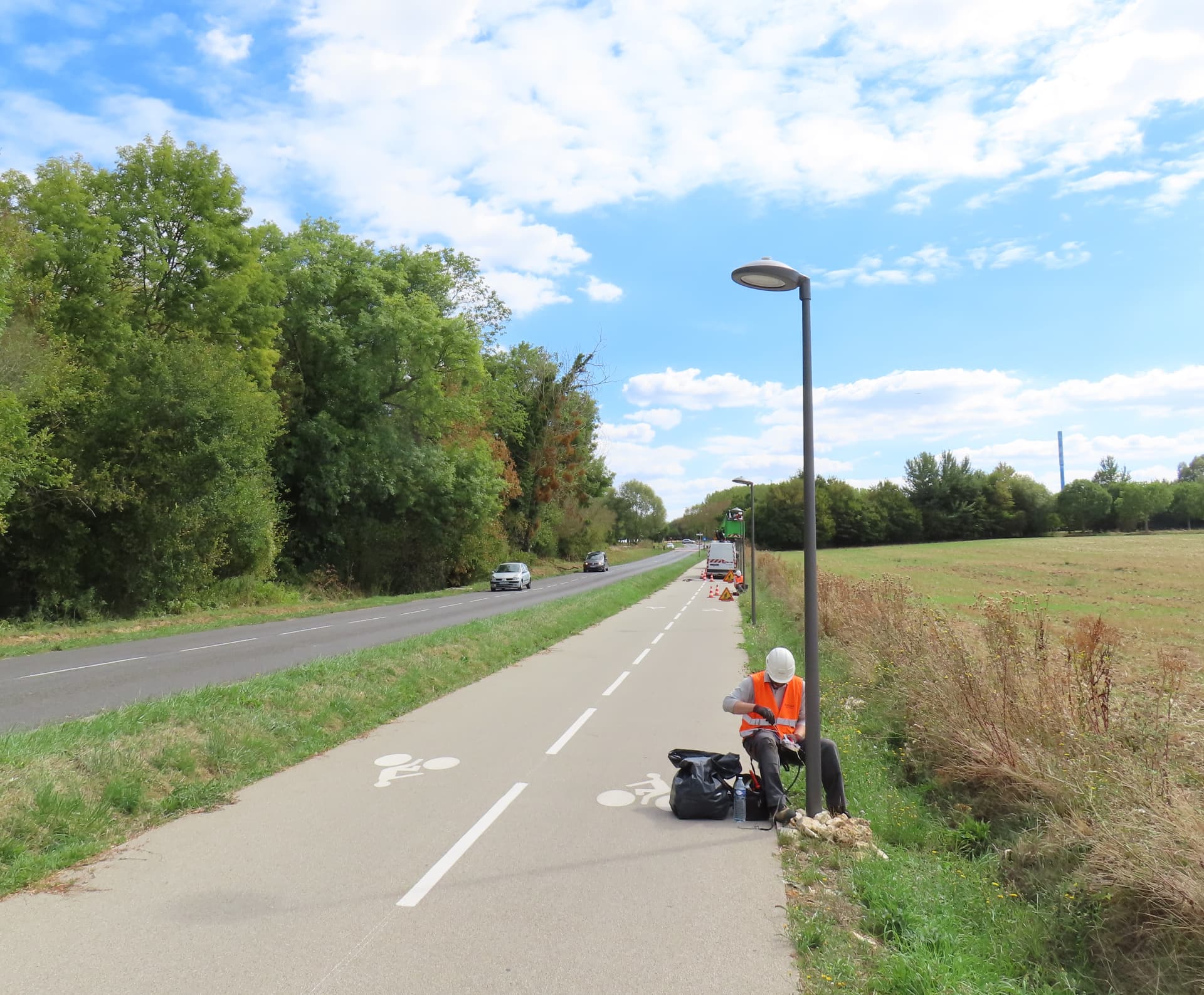 Un technicien installe un module de télégestion sur un candélabre de la piste cyclable V4